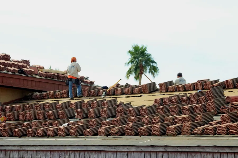 Instaladores trabajando sobre una cubierta de teja curva