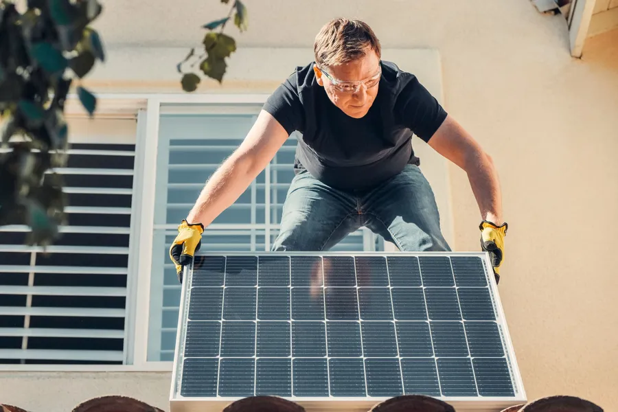 Instalador fijando una placa solar sobre la estructura de una cubierta